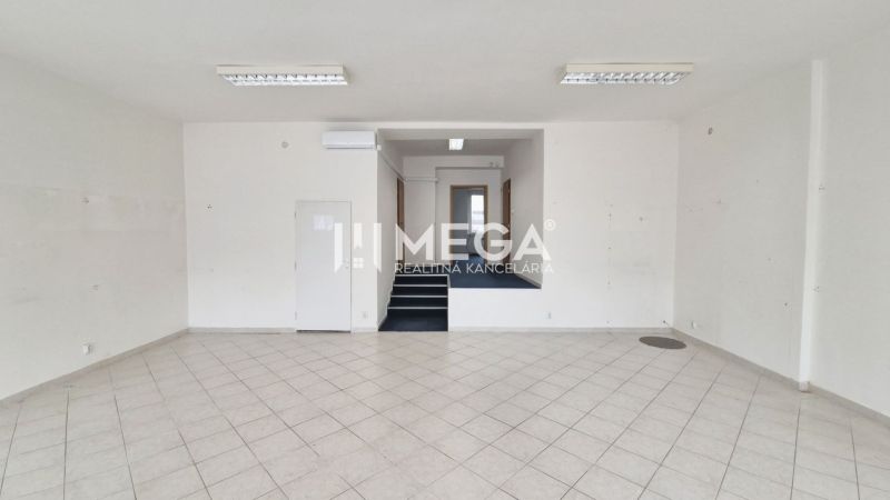 Commercial space with white walls and tiles, stairs lead to a higher level.