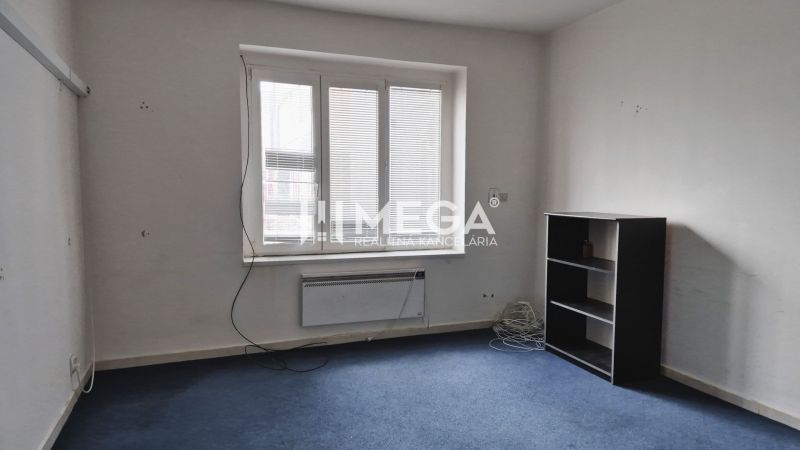 Room with carpeted floor, shelves, and a window in commercial premises.