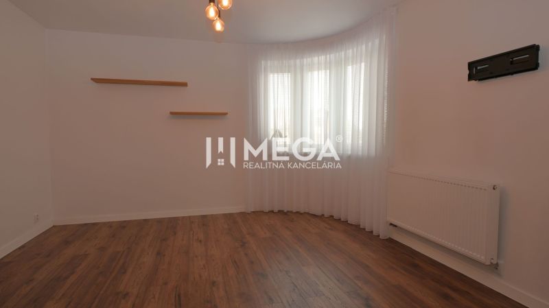 A room in a family house with a wooden decor floor, white walls, and curtains.