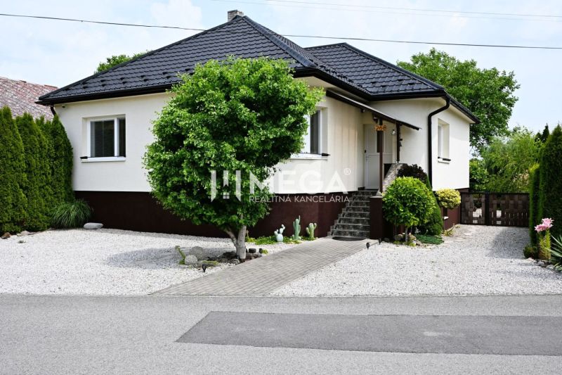 A family house in Udavské with a landscaped garden, a walkway, and ornamental shrubs.