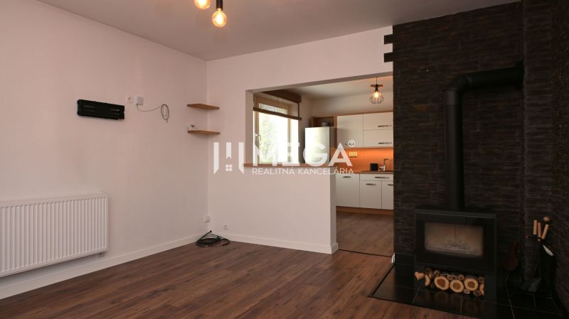 Interior of a family house with a fireplace, wooden decor flooring, and a view into the kitchen.