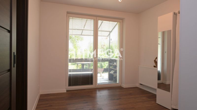 A room with a wooden decor floor, large window, radiator, mirror. Family house.