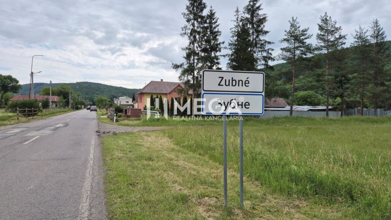 A landscape in Zubné with a road and green residential plots.