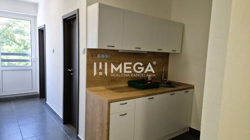 A kitchenette in the office with wooden decor and a large window.