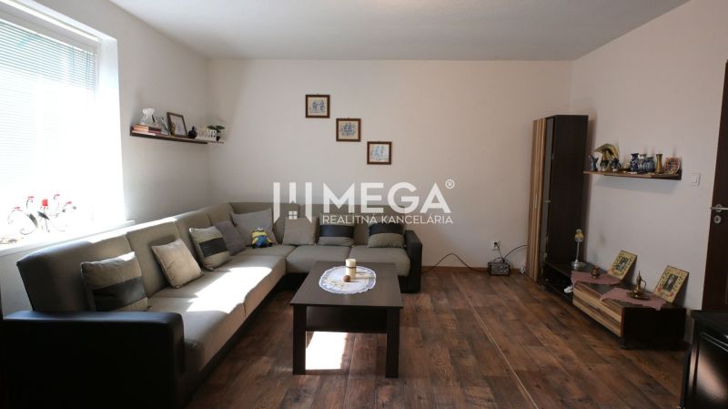 Living room with a sofa, table, and wooden decor flooring in a family house.