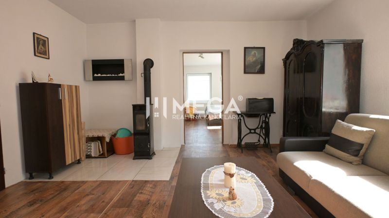 Living room in a family house with tiled stove and wood-patterned flooring.