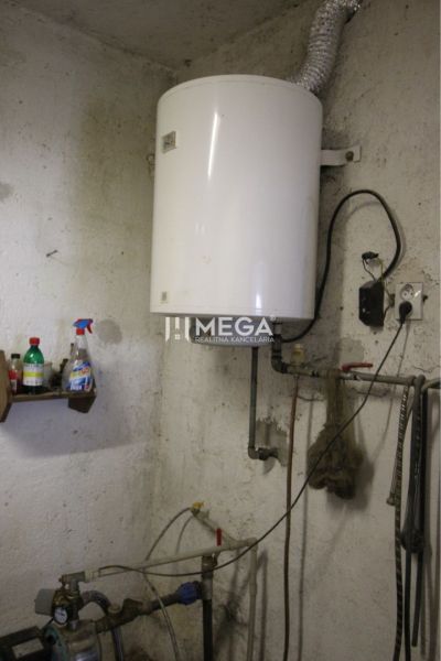 A boiler in the utility room of a family house with wall-mounted tanks.