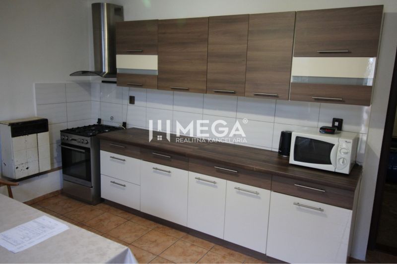 A kitchen in a family house with a wooden decor, a cooktop, a microwave, a fan.