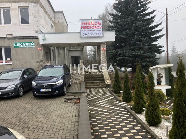 A building on SNP Street in Snina with a parking lot and an advertisement for space rental.