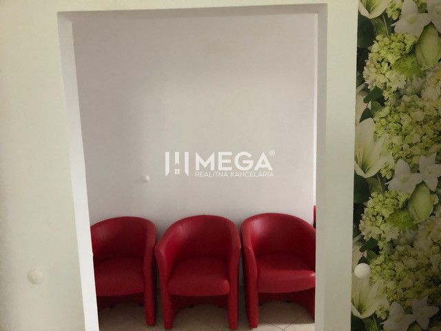 Three red armchairs with white walls and floral wallpaper in a building.