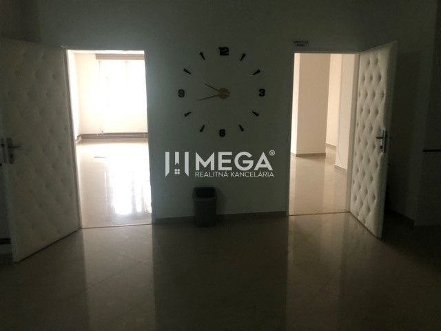 The interior of a building with prominent clocks on the wall and open doors.