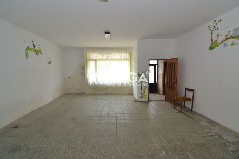 Interior of commercial premises with ceramic flooring, a drawing on the wall, and a chair in the corner.