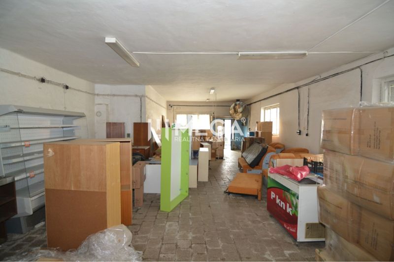 Commercial premises with stored shelves, boxes, and equipment, floor with wooden decor.