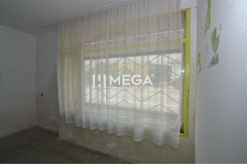 Commercial premises with curtains, a window grille, and worn-out walls.
