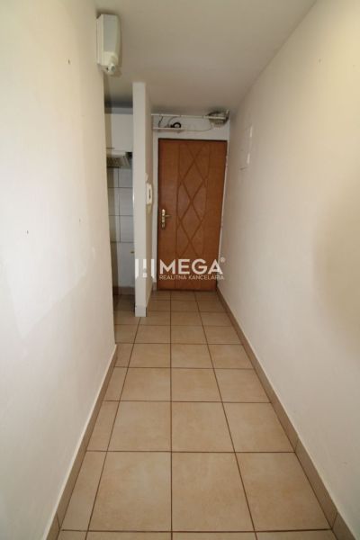 A narrow hallway with tiles and wooden doors in a 3-room apartment.