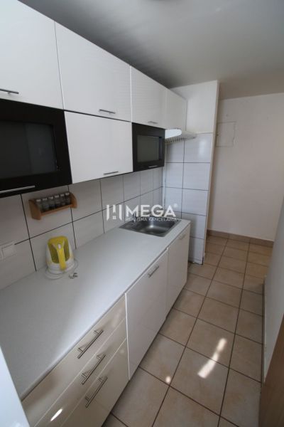 A kitchen in a 3-room apartment with white cabinets and tiled flooring.