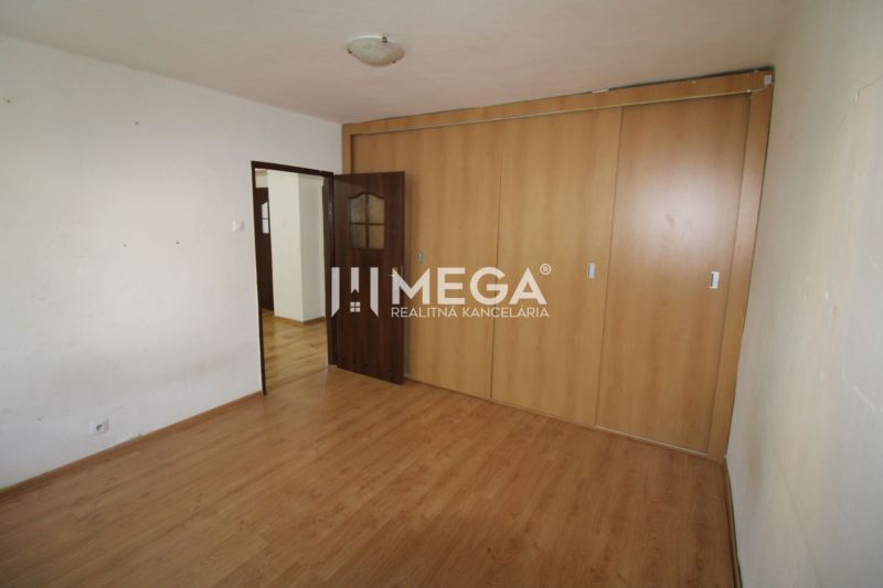 A room in a 3-room apartment with a wooden decor floor and a built-in wardrobe.