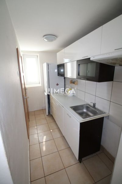 A kitchen in a 3-room apartment with white cabinets and ceramic tiles.