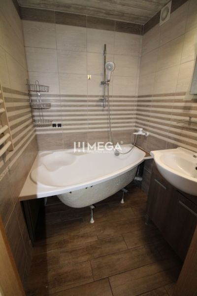 A bathroom with a bathtub and a sink in a 3-room apartment. Floor with wood decor.