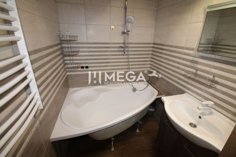 A bathroom in a 3-room apartment with a corner bathtub and a floor with a wooden decor.
