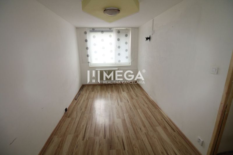 A narrow room with a window and a wooden decor floor in a 3-room apartment.