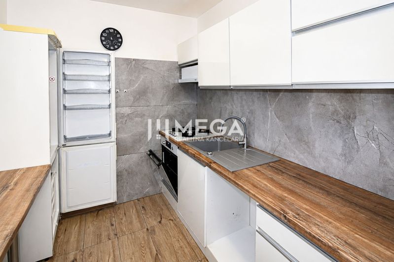 A kitchen in a 3-room apartment with a wooden decor floor and modern appliances.