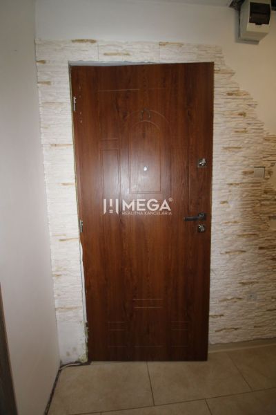 Entrance wooden door in a 3-room apartment with light stone cladding.