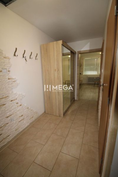 Hallway of a 3-room apartment with a tiled floor, mirrored wardrobe, and a wall with stone cladding.