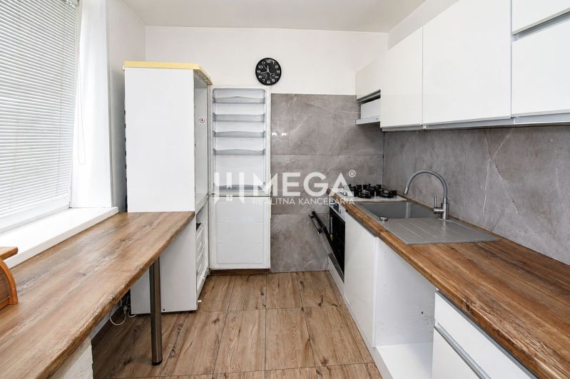 A kitchen in a 3-room apartment with a wooden decor floor and an elegant kitchen unit.