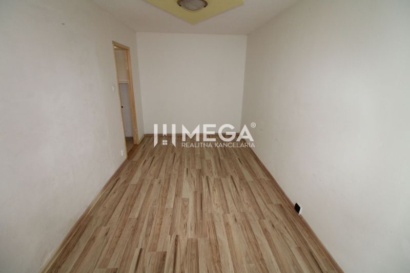 A room in a three-room apartment with a wooden decor floor and white walls.
