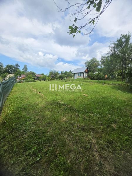 A view of the green gardens in Snina with visible cottages and a blue sky.