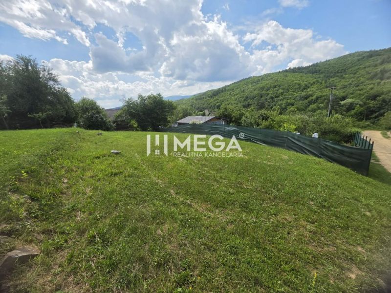 Gardens with green lawns in Snina on Snina Street surrounded by wooded hills.
