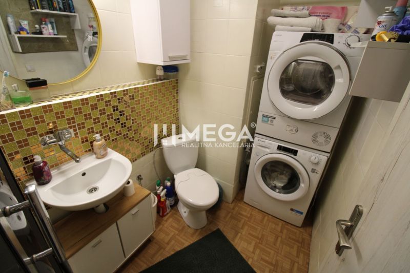 Bathroom in a 2-room apartment with a washing machine and dryer, tiles with a wooden decor.