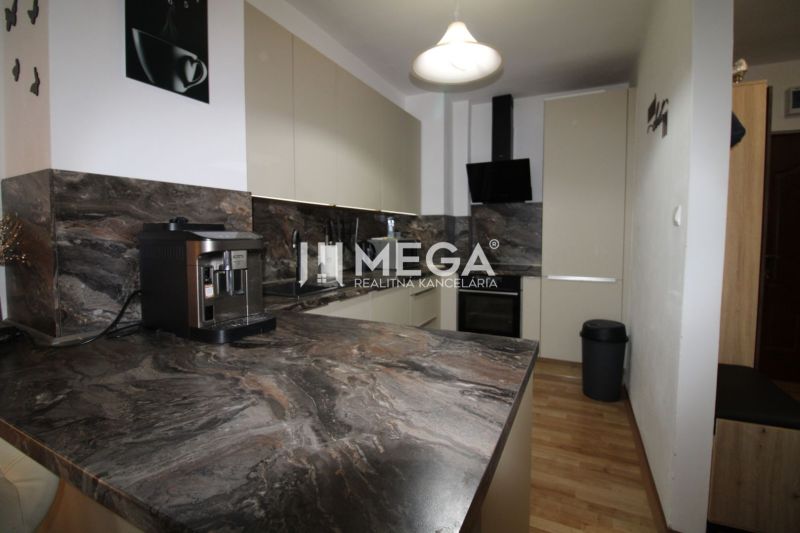 A kitchen in a 2-room apartment with a dark marble decor and a wooden decor floor.