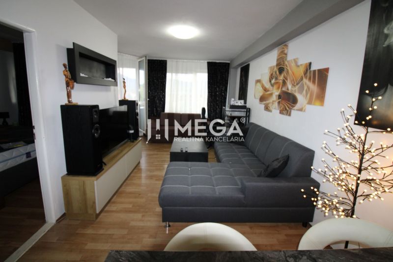 Living room in a two-room apartment with a wooden decor floor and a gray sofa.