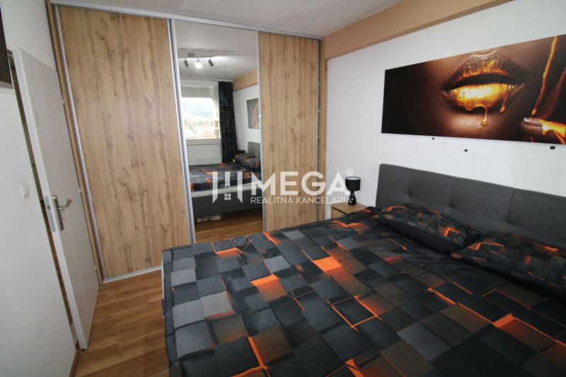 Bedroom with a bed and a wardrobe with sliding doors, floor with wood decor.