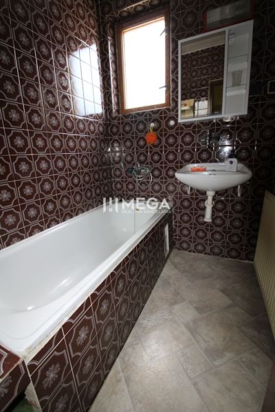 A bathroom in a family house with brown tiles and a bathtub.