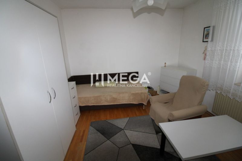 A room in a family house with a bed, an armchair, a table, and a floor with a wooden decor.