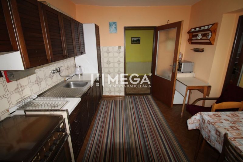 A kitchen in a family house with dark cabinets, carpet, and a wooden decor floor.