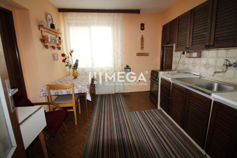 A kitchen in a family house with furniture, a carpet, and a wooden-decor floor.