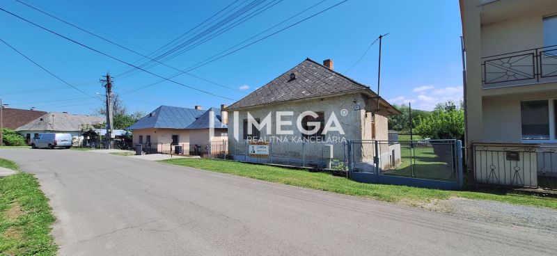 A family house in Kochanovce on Kochanovce Street, with a lawn and a fence, clear sky.