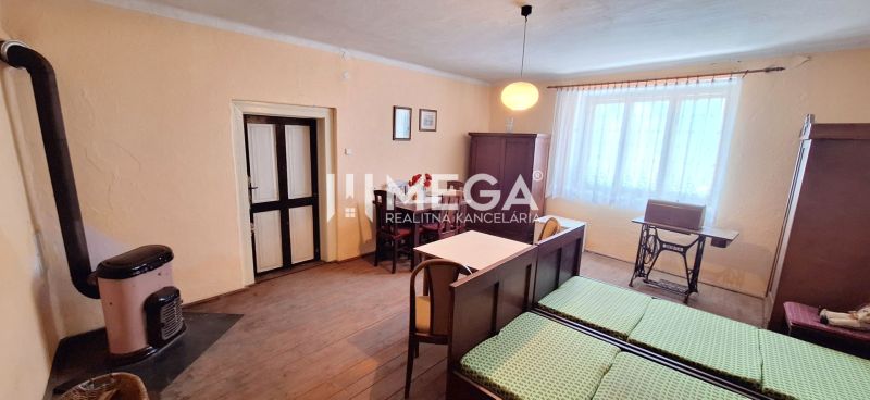 A room in a family house with a stove, a table, and a bed, with a wooden decor floor.