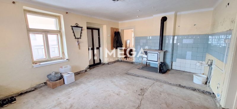 Interior of a family house with a tiled stove and a wallpapered wall on a floor with a wooden decor.