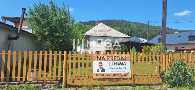 The family house for sale in the village of Kochanovce stands behind a fence with greenery.