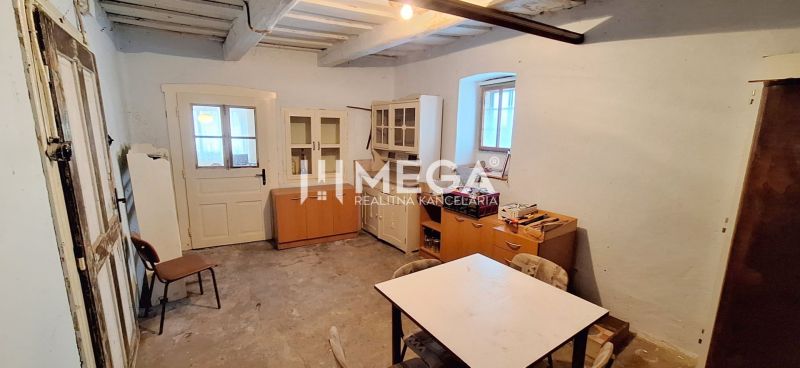 A room in a family house with older furniture and a table, without decorative flooring.