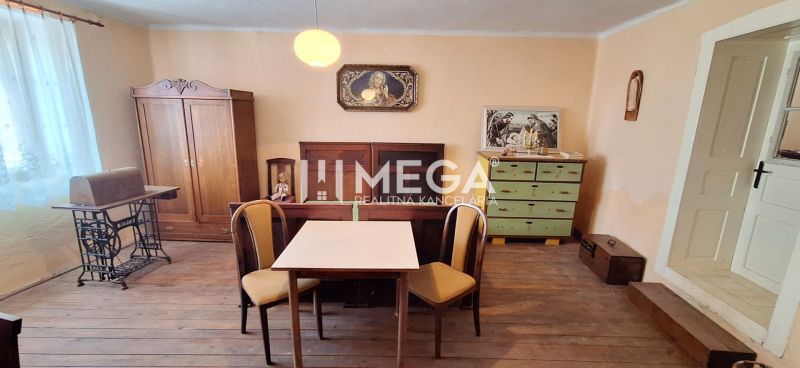 A room in a family house with a wooden decor floor, a table, chairs, and antique furniture.