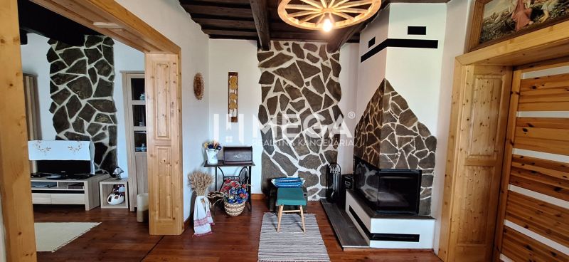 Interior of a family house with a fireplace, stone walls, and a floor with a wooden decor.