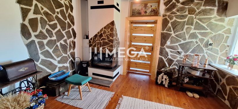 A room in a family house with a fireplace, stone walls, and a floor with a wooden decor.