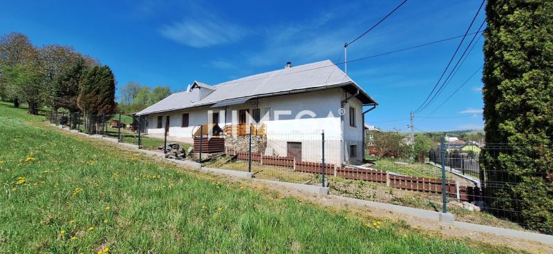 A family house in the village of Zbudská Belá surrounded by green lawns and trees.