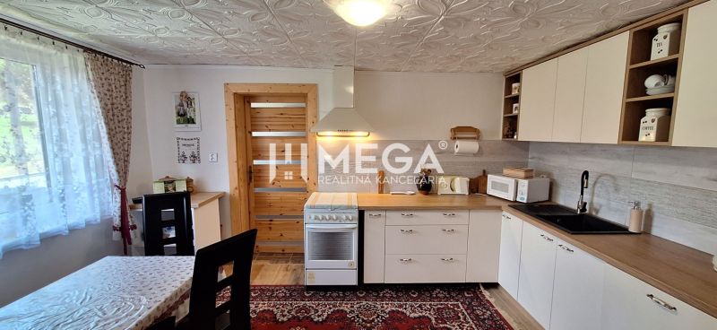 A kitchen in a family house with a carpet, kitchen unit, and curtains by the table.
